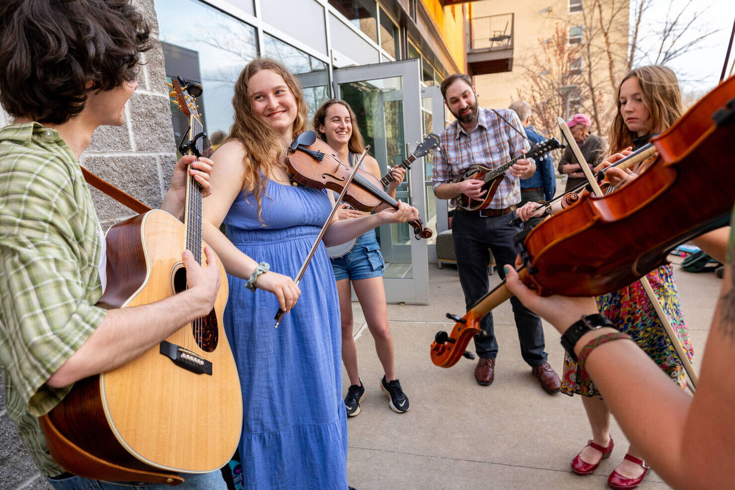 students playing string instruments on sidewalk